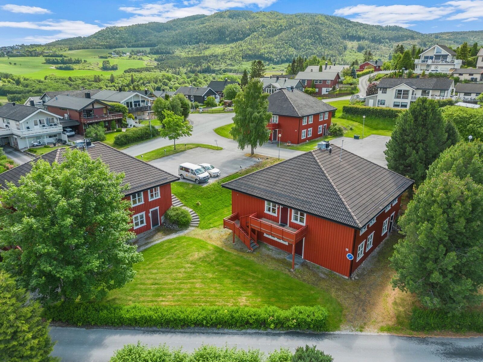 To av boligene med plen og parkering, fjellet i bakgrunnen